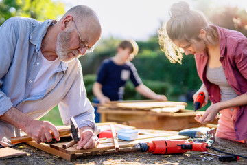 A man and his family are building wooden planters for their vegetable garden - Powered by Adobe