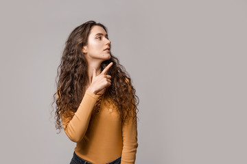 Look over there! Woman consultant in yellow on a white background shows a finger to the left. Copy space place for incept advertising, text or logo. People lifestyle concept.