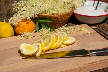 On a cutting board lies a kitchen knife and a sliced organic lemon, in the background you can see...