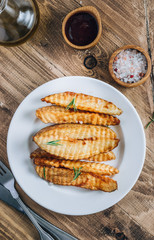 Baked potato fries with sea salt and rosemary on a rustic wooden background.