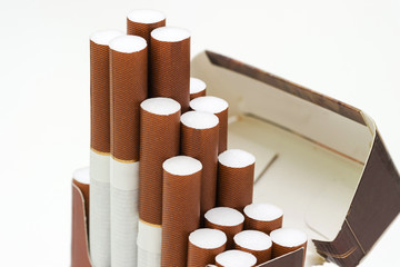 Cigarettes with a brown filter in a pack of cigarettes on a white background. Tobacco industry.