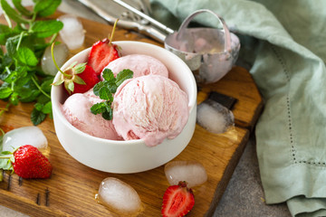 Homemade Organic Strawberry Ice Cream. Strawberry ice cream balls with mint leafon a light stone or slate table.