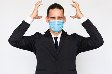 Work stress - Angry young businessman wearing blue anti virus medical mask. Business man portrait isolated against white background.