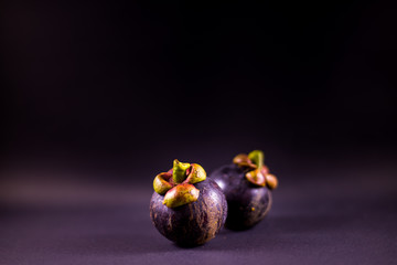 Ripe mangosteens in black background, Fresh mangosteens with dark background.