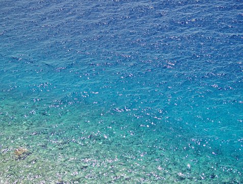 Turquoise translucent croatian sea with shallow water and pebbles on the bottom with sparkles on the watertable