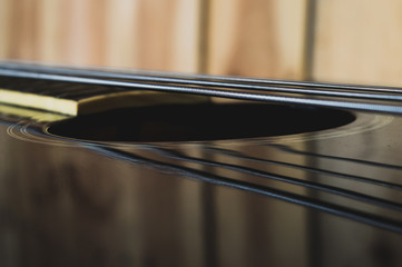 Closeup on the strings and body of a black acoustic bassguitar