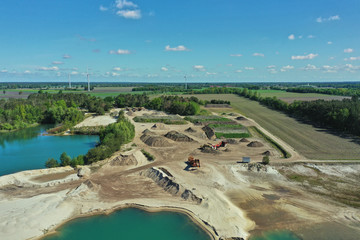 Aerial view of the storage area of a sand mining site with sand heaps, gravel heaps and machines for mining