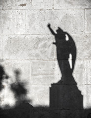 shadow of the statue of an angel projected on a wall