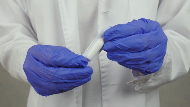 Proctologist opening hemorrhoidal suppository, closeup