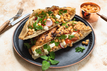 Healthy vegetarian tortilla or pita bread with chickpeas, vegetables and herbs served with homemade hummus in vintage dishes. Healthy eating concept. Light background. Close-up. Copy space