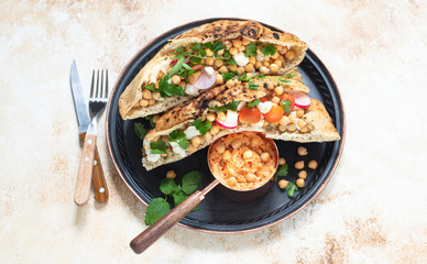 Healthy vegetarian tortilla or pita bread with chickpeas, vegetables and herbs served with homemade hummus in vintage dishes. Healthy eating concept. Light background. Top view. Copy space