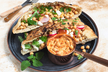 Healthy vegetarian tortilla or pita bread with chickpeas, vegetables and herbs served with homemade hummus in vintage dishes. Healthy eating concept. Light background. Close-up. Copy space