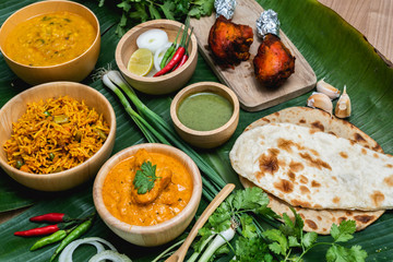 Assorted indian food, biryani rice, butter chicken, tandoori, bean curry and naan bread