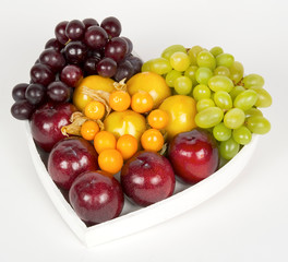 Assorted fresh fruits in white wooden heart shaped box.White background. close view. top view. isolated

