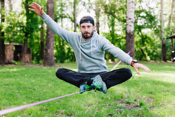 Young man balancing and jumping on slackline. 