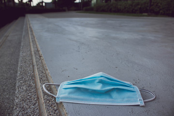 Blue disposable medical mask is on the road surface, on street. to prevent the Virus Covid-19. Concept viruses spread throughout the world. Do not throw away your used face mask. copy space.