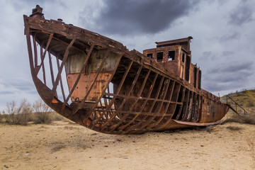 Fototapeta na wymiar Rusting ship at the Ship Cemetery near Moynaq village at the former coast of Aral Sea, Uzbekistan