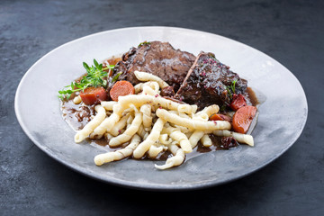 Traditionelle deutsche geschmorte Ochsen Schmorbacken in brauner Rotwein Sauce mit Nudeln und...