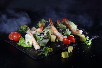 Caesar salad with king prawns on a dark background. Effectively Served Caesar Salad