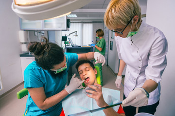 Male dentist and female assistant showing a young boy patient his teeth x-ray image in the dental office.