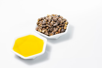 castor oil and grains in bowl isolated on white background