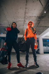 Two female boxer friends standing in a garage with boxing equipment