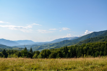 Fototapeta na wymiar Landscape of bright summer day in Carpathian mountains, panorama of Carpathians, blue sky, trees and green hills, beautiful view