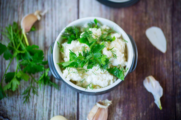 salted homemade cottage cheese with garlic and herbs in a bowl