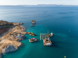 Aerial view of machinery at the construction of future LNG terminal on the shore of the bay in Omisalj, Croatia