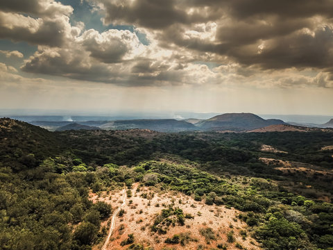 Aerial View of Forest and Hillside with sunrays piercing through the clouds above a single path in Rincon de la Vieja National Park in Costa Rica