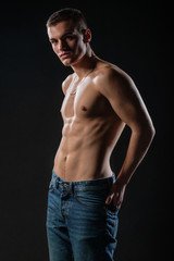 Fototapeta na wymiar Portrait of a strong healthy handsome athletic man posing as a fitness model on dark background