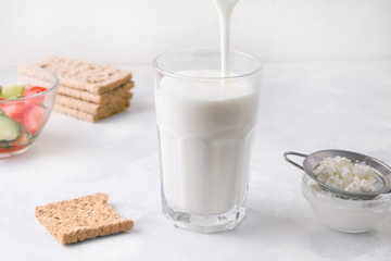Fermented kefir yogurt is poured into a glass on a white background. Healthy breakfast concept