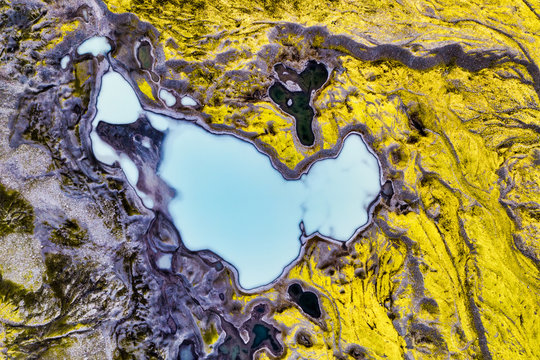Aerial view of the colourful landscape around the blue lake, Iceland. While the lakes are blue, the yellow comes from the lichens and grey from the gravel.