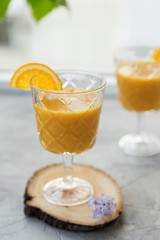 Tropical fresh smoothie in glass with garnish at gray background