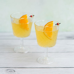 Fresh lemonade with garnish in glasses on bright wood background