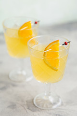 Glass with orange lemonade with slice of orange at toothpicks at bright white background