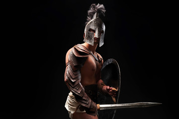 Fototapeta na wymiar Gladiator with sword and armor on a black background