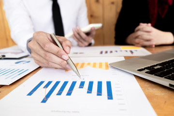 Two business people are presenting and discussing about business graph for sales plan in the office.