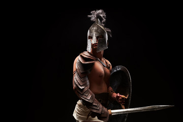 Obraz na płótnie Canvas Gladiator with sword and armor on a black background