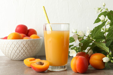 Composition with tasty apricots and juice on gray table