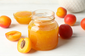 Composition with tasty apricots and jam on white wooden table