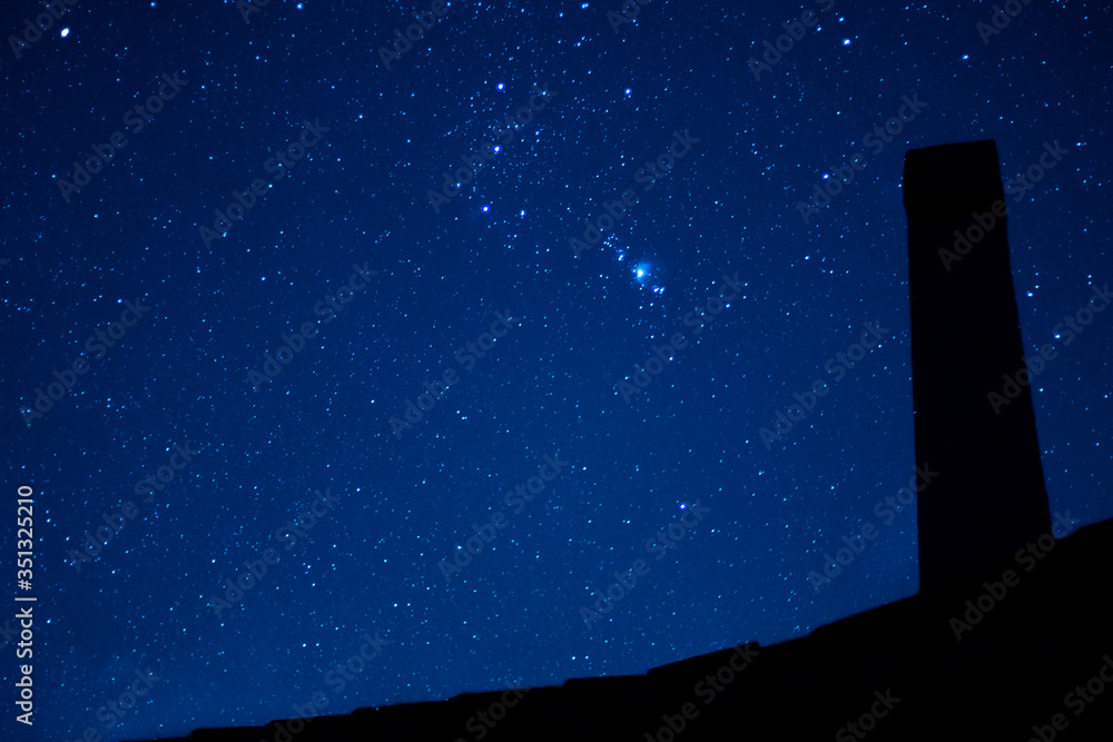 Wall mural image of the starry sky with the silhouette of an ancient fireplace