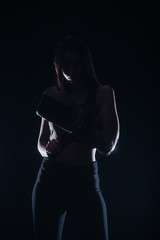 Fototapeta na wymiar Silhouette portrait of a sexy fit woman posing in dark contrast with boxing gloves