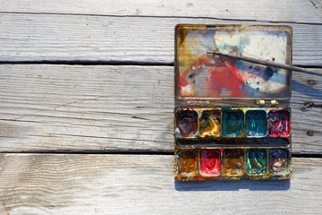 Box with old mixed paints and small brush, copy space.