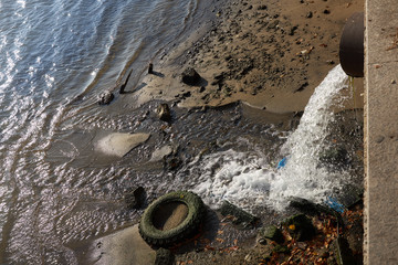 From a large pipe, sewage discharges into the river after rain.