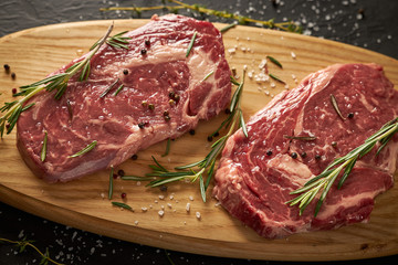 Two juicy slices of ribeye steak lie on a wooden board.