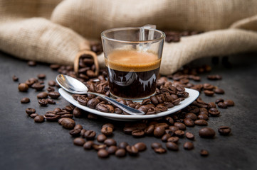 espresso coffee in a glass cup on a black floor with coffee beans cutting light