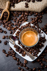Italian espresso coffee in a glass cup on a black floor with coffee beans cutting light