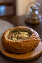 typical polish soup inside a bread roll called zurek, with meat mushrooms and potatoes