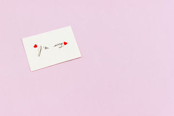 The words I'm sorry handwritten on a white card decorated with two confetti hearts. Empty space.